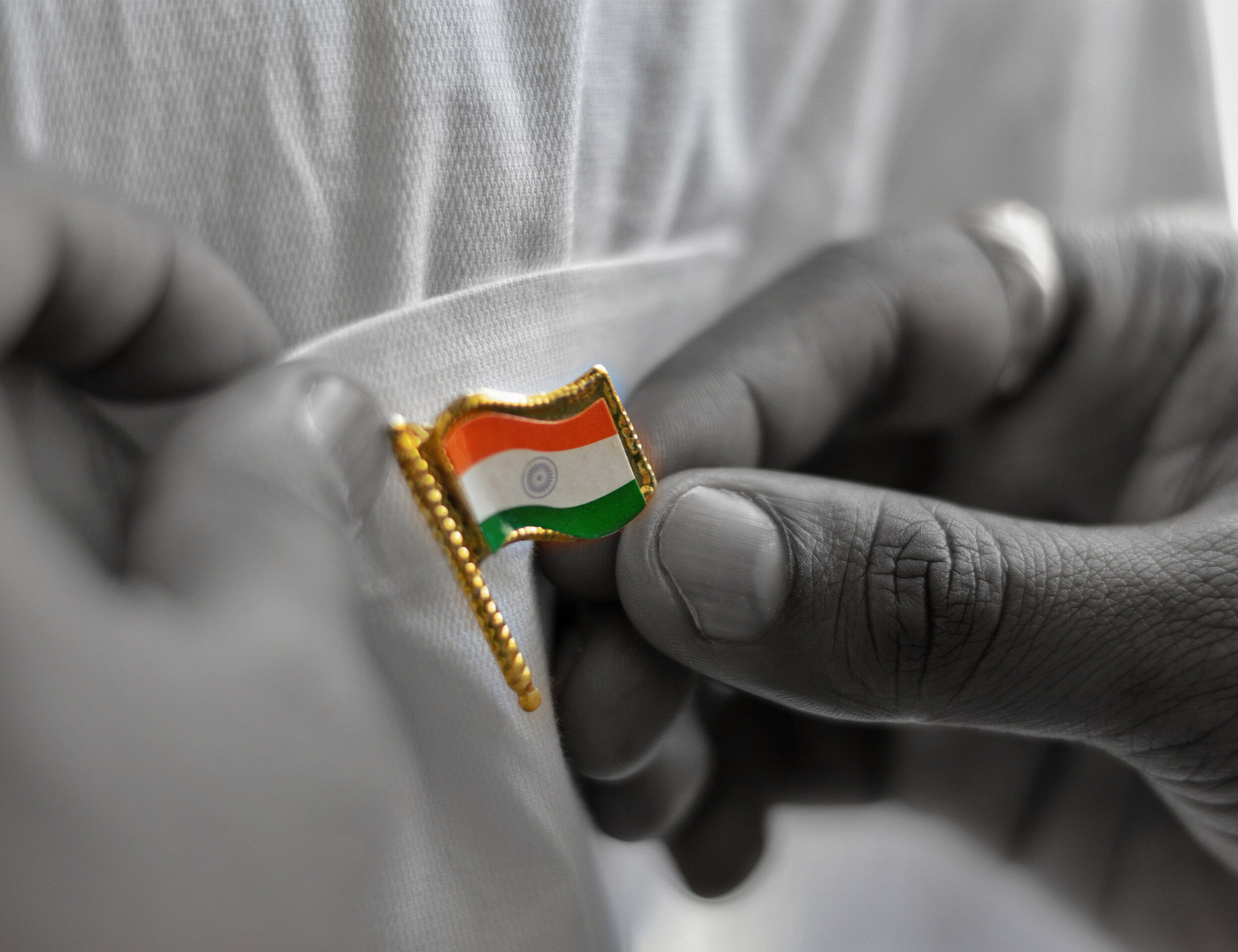 Close-up of a person pinning the Indian national flag badge on a white kurta for Independence Day celebration.